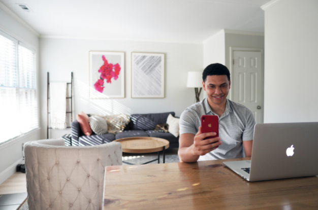 image of man happy to be investing on this phone with a laptop