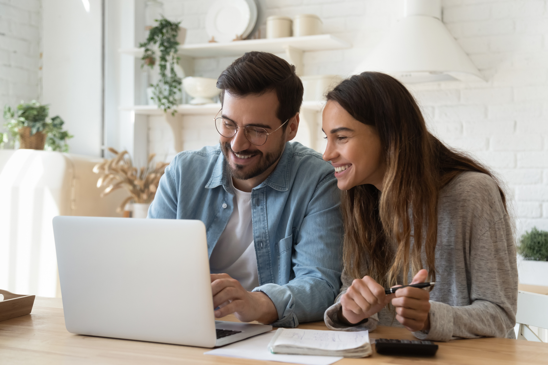A couple at a kitchen table reviewing retirement options on a laptop.